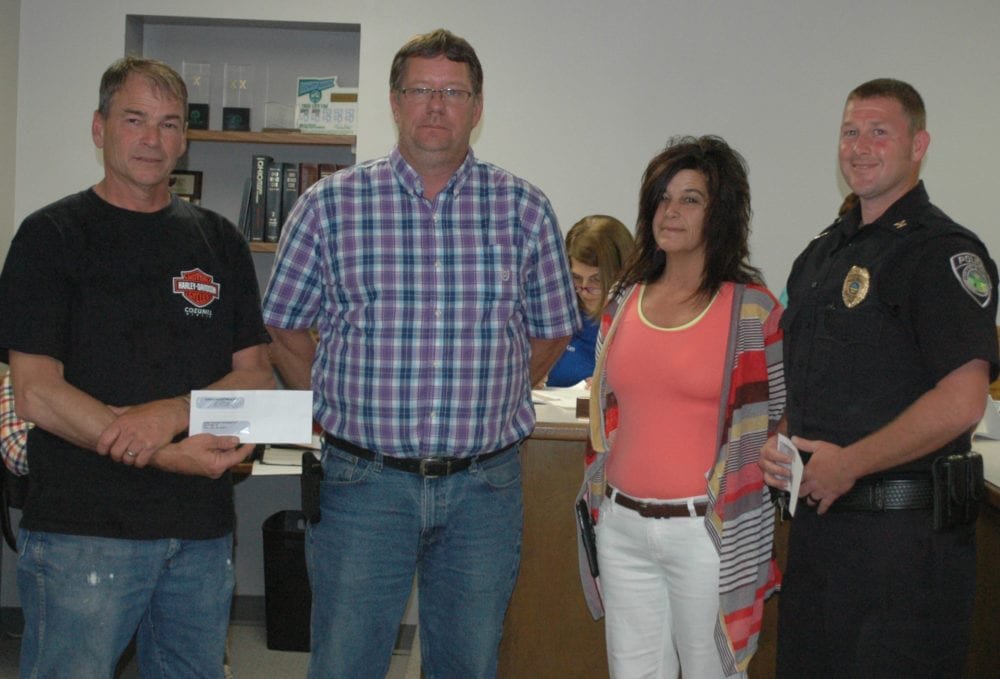 Kamco Executive Vice President Alan Benien (left center) and Kamco Plant Manager Lisa Woodring (right center) attended the meeting of the West Unity Village Council to give thanks to the community by donating to both the Brady Township Fire Department, represented by Jim Eisel (left) and the West Unity Police Department, represented by Police Chief J.R. Jones (right).